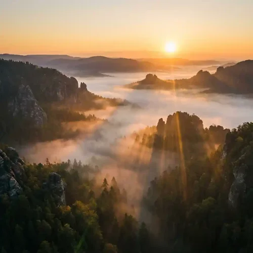 Cinematic drone shot of misty mountains at sunrise with golden hour light.